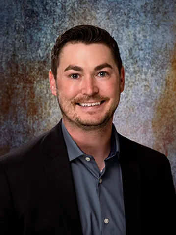 A man in a suit and tie smiling for the camera.