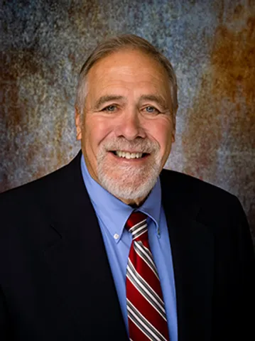 A man in a suit and tie smiling for the camera.