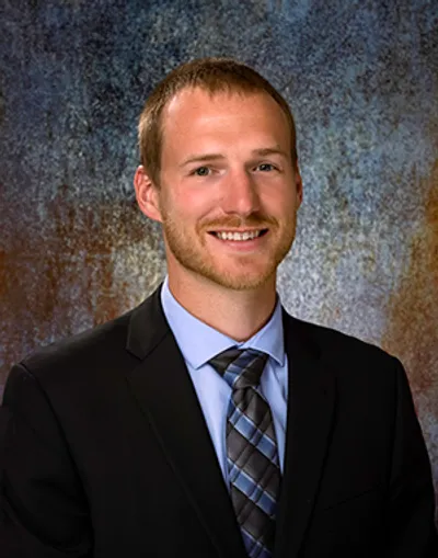 A man in suit and tie smiling for the camera.