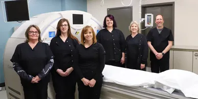 A group of women standing in front of an mri machine.