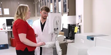 A man and woman in lab coats looking at computers.