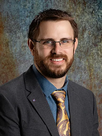 A man in a suit and tie smiling for the camera.