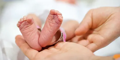 A baby 's foot is being held by its mother.