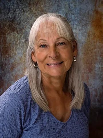 A woman with white hair is smiling for the camera.