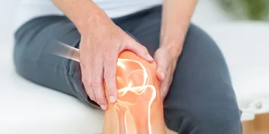 A person with knee pain is holding their hand on the ground.