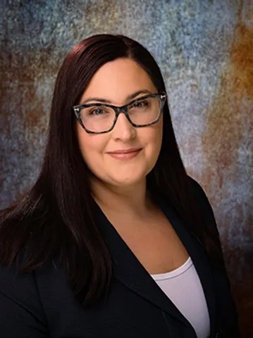 A woman with glasses and long hair wearing a black jacket.