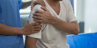 A man holding his shoulder in the arm of another person.