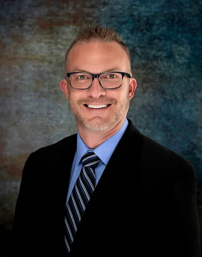 A man in a suit and tie smiling for the camera.